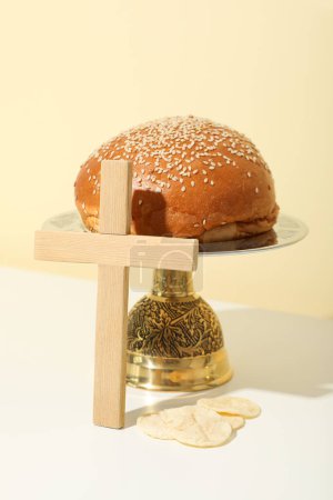Foto de Cruz de madera y pan sobre mesa sobre fondo beige - Imagen libre de derechos
