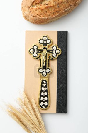 Cross on book and spikelets on white background, top view