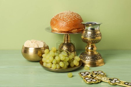 Bread, grape, golden cup and cross on green background