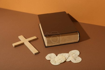 Foto de Cruz de madera, libro y pan litúrgico sobre fondo marrón - Imagen libre de derechos