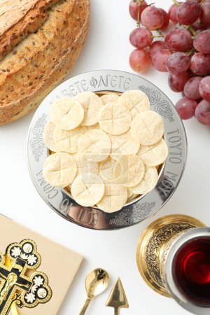 Foto de Pan, copa, uvas y cruz en el libro sobre fondo blanco, vista superior - Imagen libre de derechos