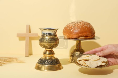 Foto de Cruz de madera, pan, mano y copa sobre fondo claro - Imagen libre de derechos