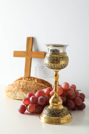 Foto de Pan, copa, uvas y cruz de madera sobre fondo blanco - Imagen libre de derechos