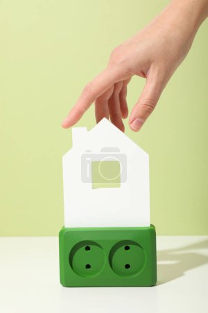 Green electrical outlet with white decorative house