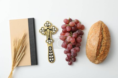 Foto de Pan, uvas, cruz y espiguillas en el libro sobre fondo blanco, vista superior - Imagen libre de derechos