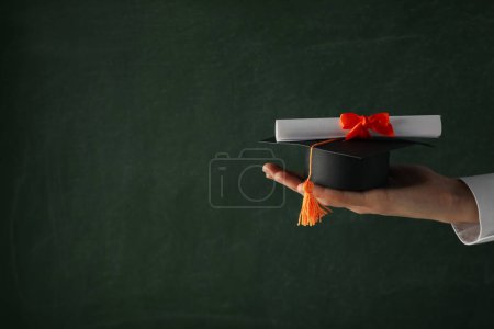 Téléchargez les photos : Chapeau et diplôme d'études supérieures en miniature, entre les mains. - en image libre de droit