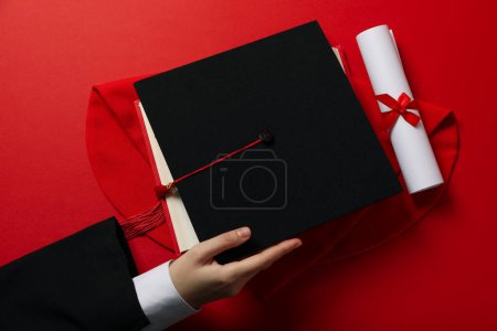 Téléchargez les photos : Chapeau diplômé avec diplôme sur fond rouge. - en image libre de droit