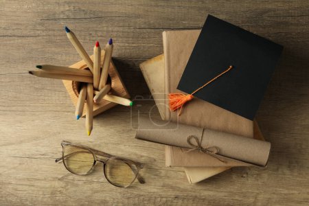 Téléchargez les photos : Chapeau diplômé et livres sur table en bois - en image libre de droit