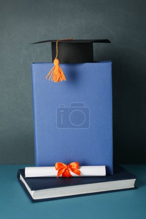 Téléchargez les photos : Chapeau et livres diplômés, sur fond bleu. - en image libre de droit
