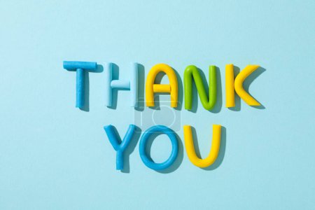 Das Wort "Danke" aus farbigem Knetmasse auf blauem Hintergrund.