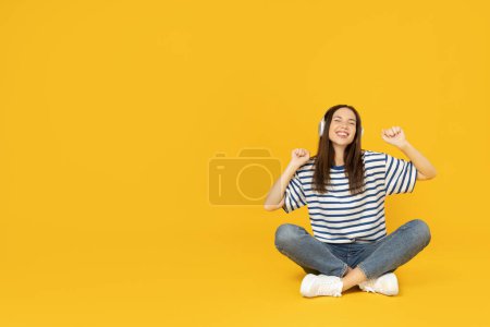 A girl in headphones listens to music, on a yellow background.
