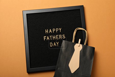 Inscription on a black board for Father's Day, on an orange background.