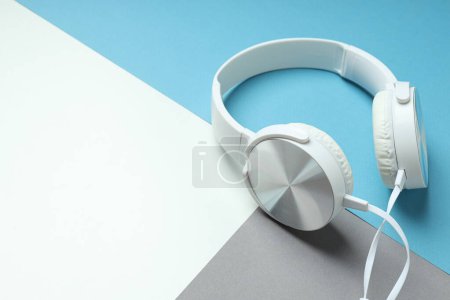 White, over-the-ear headphones with a wire on a blue background.