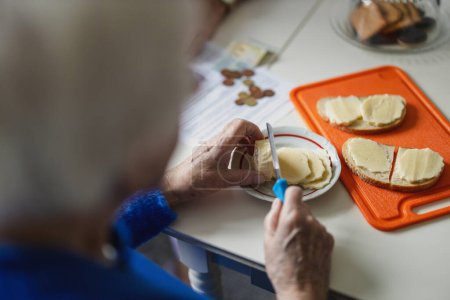 Téléchargez les photos : Gros plan sur les mains d'une femme âgée faisant des sandwichs dans la cuisine - en image libre de droit