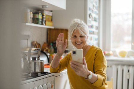 Foto de Mujer mayor usando teléfono móvil en casa - Imagen libre de derechos