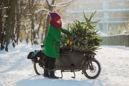 Frau transportiert Weihnachtsbaum auf Lastenfahrrad