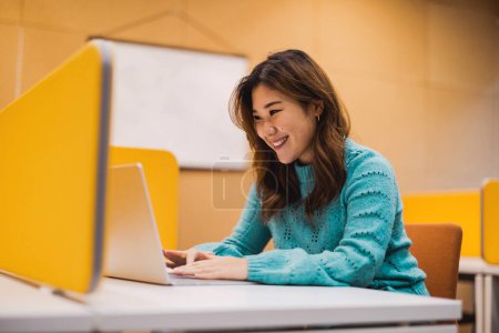 Téléchargez les photos : Étudiante travaillant sur ordinateur portable dans une cabine de bibliothèque - en image libre de droit