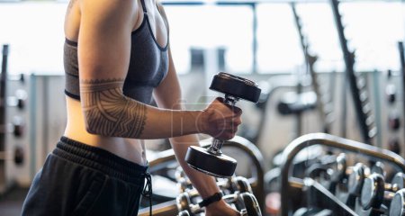 Photo for Young woman exercising with dumbbells in a health club - Royalty Free Image
