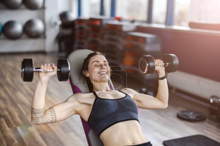 Foto de Mujer joven haciendo ejercicio con pesas en un club de salud - Imagen libre de derechos