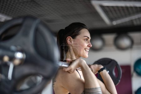 Foto de Mujer joven haciendo ejercicio con una barra en el gimnasio - Imagen libre de derechos