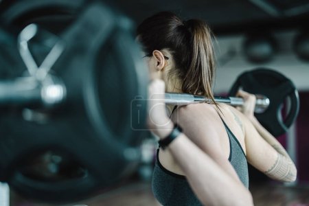 Photo for Young woman working out with a barbell at the gym - Royalty Free Image