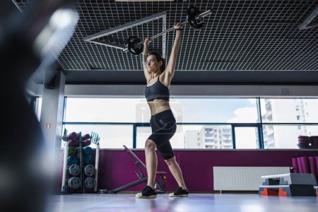 Téléchargez les photos : Jeune femme travaillant avec un haltère à la salle de gym - en image libre de droit