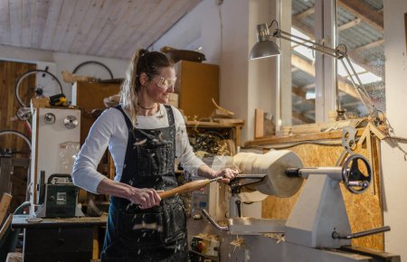 Foto de Artesana tallando madera en un taller de carpintería - Imagen libre de derechos