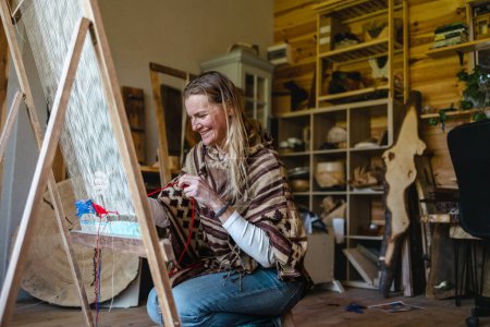Téléchargez les photos : Femme rusée tissant à un métier à tisser à son atelier - en image libre de droit