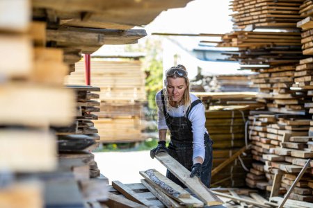 Foto de Mujer trabajando con tablones de madera en un aserradero - Imagen libre de derechos