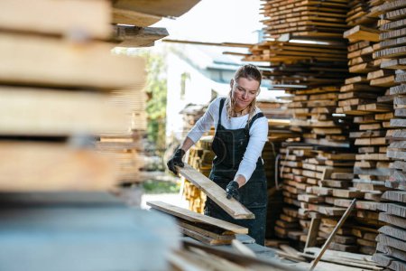 Téléchargez les photos : Femme travaillant avec des planches de bois dans une scierie - en image libre de droit