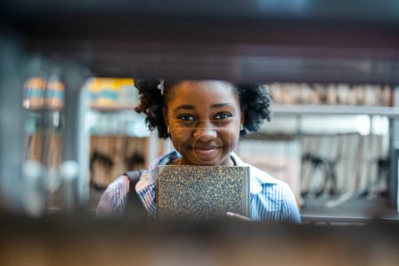 Foto de Retrato de una estudiante negra de pie en una biblioteca - Imagen libre de derechos