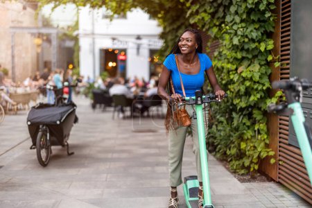 Téléchargez les photos : Portrait d'une jeune femme heureuse en scooter électrique dans la ville - en image libre de droit