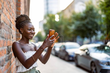 Retrato de una joven usando teléfono móvil en la ciudad