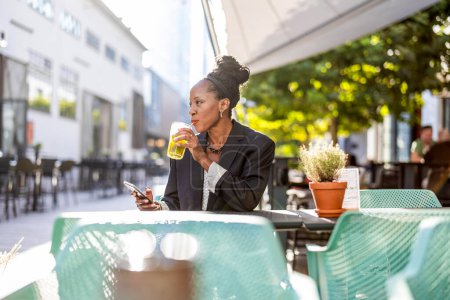 Téléchargez les photos : Portrait d'une femme d'affaires mature assise dans un café extérieur - en image libre de droit