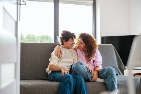 Photo for Happy mother and son sitting on sofa in living room at home - Royalty Free Image