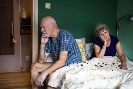 Téléchargez les photos : Couple âgé est assis sur le lit ayant des problèmes relationnels - en image libre de droit