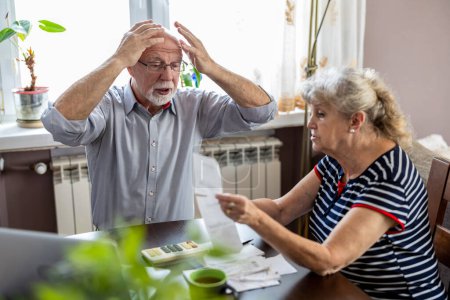 Téléchargez les photos : Couple de personnes âgées discutant de leurs finances à la maison tout en étant assis à la table - en image libre de droit