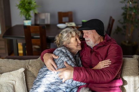 Téléchargez les photos : Couple âgé portant des vêtements d'hiver à l'intérieur de la maison en raison des prix élevés de l'électricité - en image libre de droit