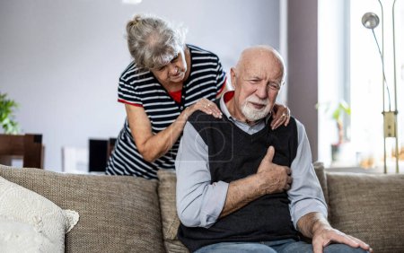 Foto de Hombre mayor que sufre de dolor en el pecho mientras su esposa lo consuela - Imagen libre de derechos