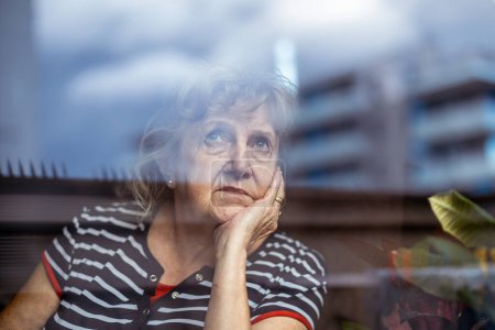 Foto de Retrato de mujer mayor mirando por la ventana - Imagen libre de derechos