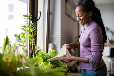 Photo for Beautifulwoman watering plants at home - Royalty Free Image