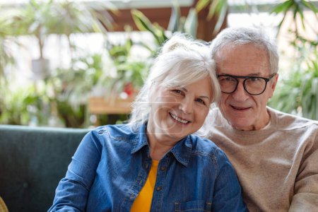 Foto de Retrato de una feliz pareja de ancianos sentados en el sofá en casa - Imagen libre de derechos