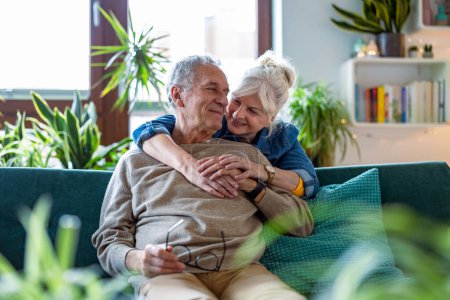 Téléchargez les photos : Portrait d'un heureux couple de personnes âgées assis sur un canapé à la maison - en image libre de droit