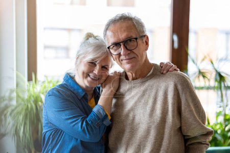 Foto de Retrato de feliz pareja de ancianos abrazándose en la sala de estar en casa - Imagen libre de derechos