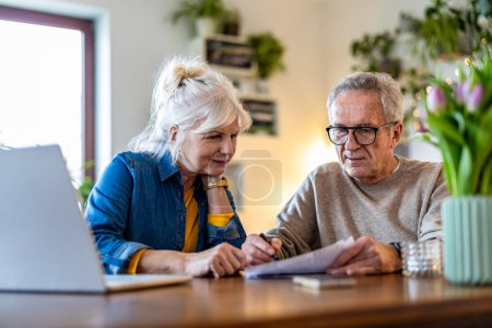Téléchargez les photos : Couple âgé assis à la table pour discuter des finances de la maison - en image libre de droit