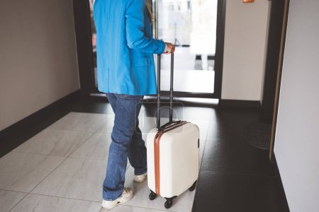 Foto de Mujer joven con una maleta en el pasillo del hotel - Imagen libre de derechos