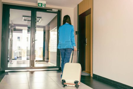 Mujer joven con una maleta en el pasillo del hotel
