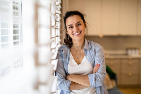 Téléchargez les photos : Portrait d'une belle jeune femme debout dans la cuisine à la maison - en image libre de droit