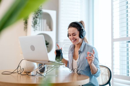 Téléchargez les photos : Femme portant des écouteurs assis à un bureau parlant dans le microphone et enregistrant un podcast - en image libre de droit
