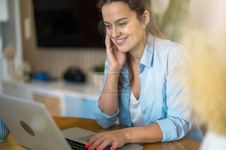 Foto de Retrato de la mujer sonriente trabajando en el ordenador portátil en casa - Imagen libre de derechos